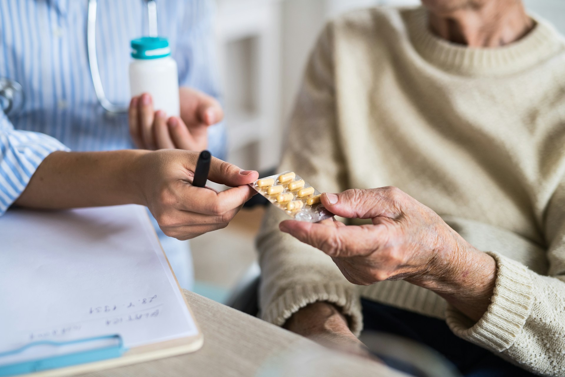 Healthcare professional handing medication to an older adult during a medication review consultation.